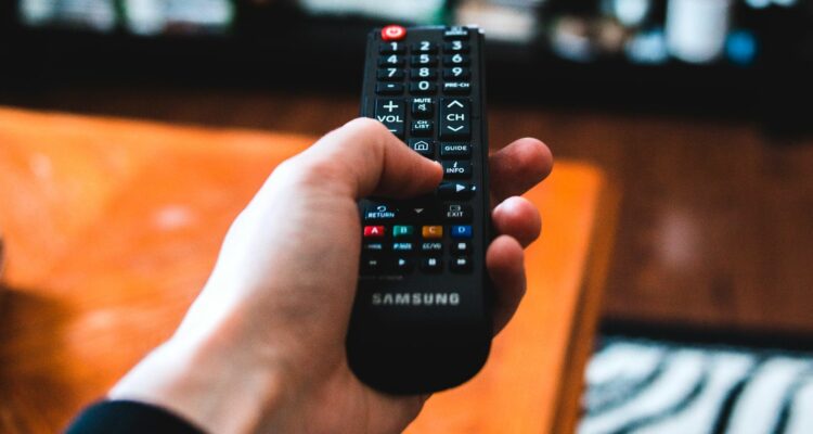 person using remote control to change tv channel feature1 06kUDl
